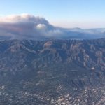 Aerial photo of mountain range with smoke plume in the background