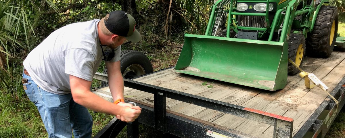 District staff member unloads a tractor from a trailer