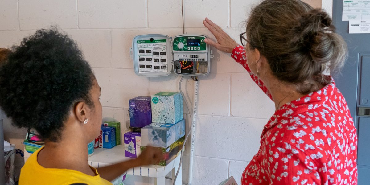 Single mom saves water eirdre Irwin shows Miky Ynirio how to adjust her lawn sprinkler timer