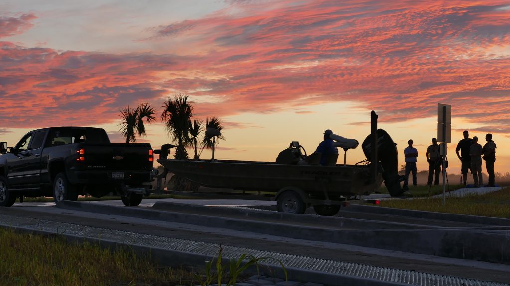 An angler backs their boat into the water at dawn