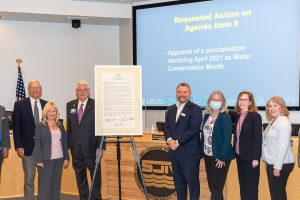 Governign board members with poster sized water conservation month proclamation