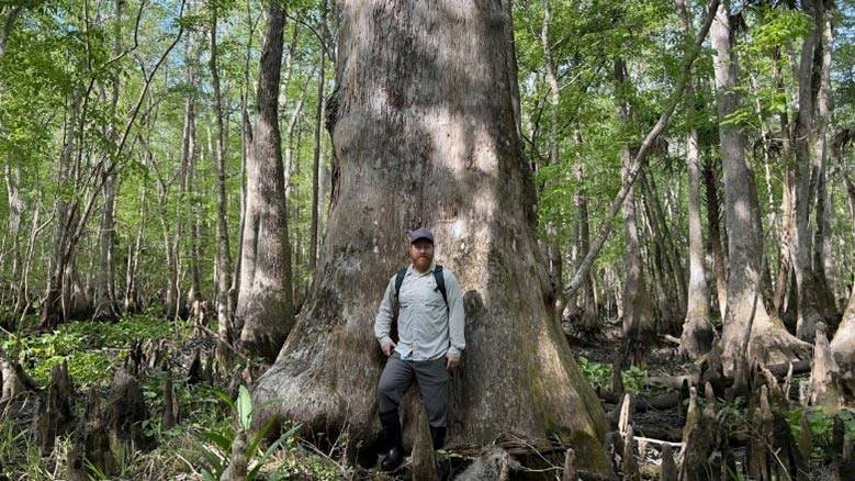 Man standing next to a large tree